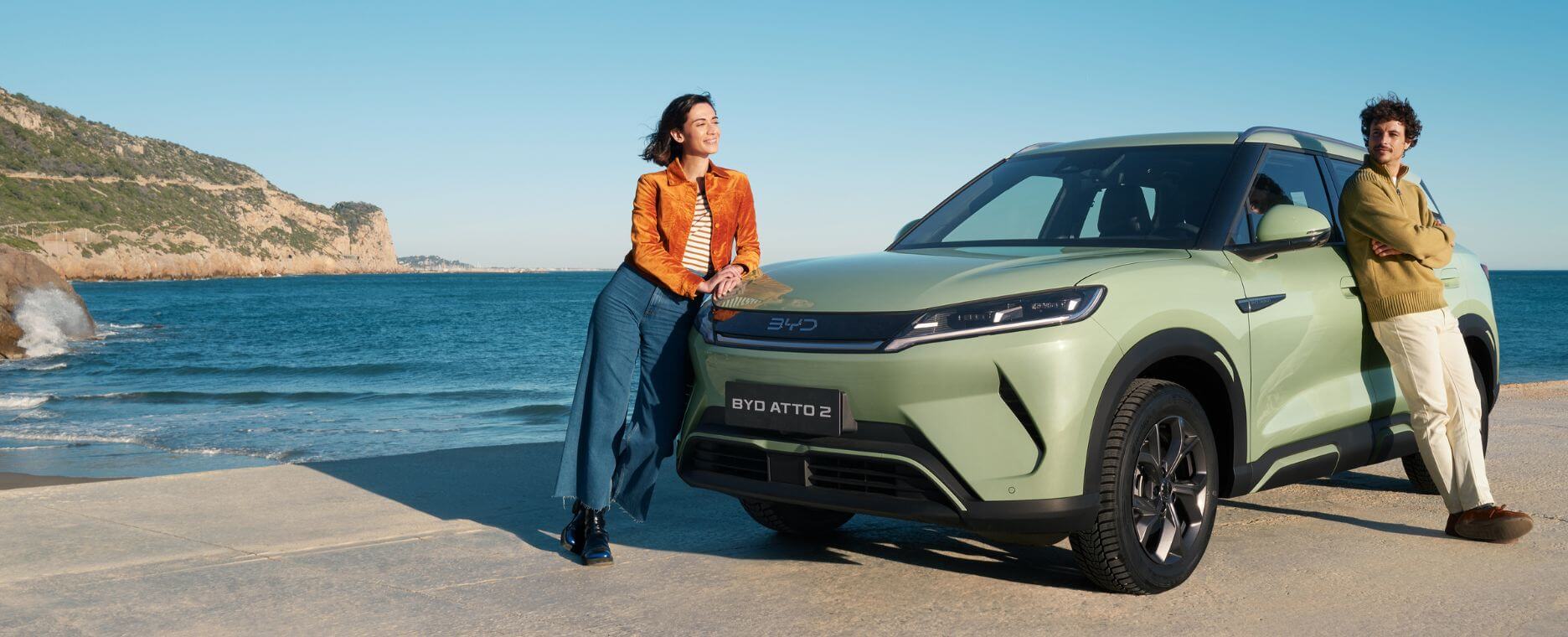 Vrouw die tegen de motorkap van de BYD ATTO 2 leunt.